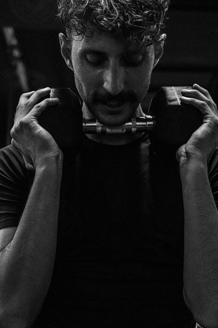 A focused man lifting a dumbbell during a monochrome workout session.